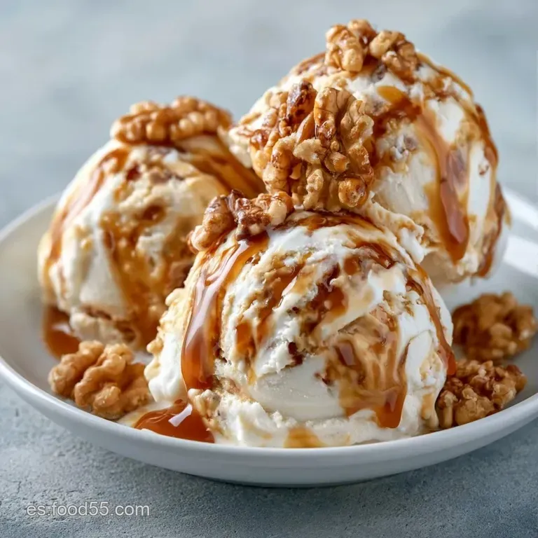 Copa de cristal con helado vainilla, hilos brillantes de caramelo &aacute;mbar y nueces enteras sobre un fondo neutro.